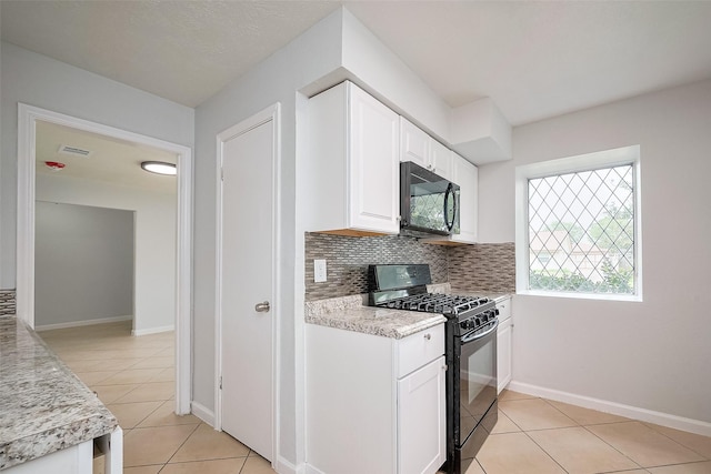 kitchen featuring tasteful backsplash, light tile patterned floors, baseboards, white cabinets, and black appliances