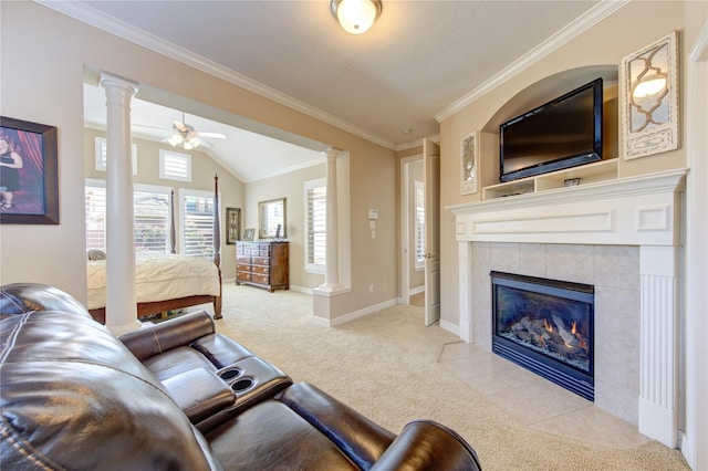 living room with a ceiling fan, decorative columns, light carpet, ornamental molding, and a tiled fireplace