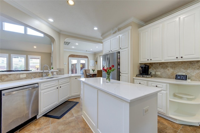 kitchen with stainless steel appliances, a sink, ornamental molding, tasteful backsplash, and white cabinets