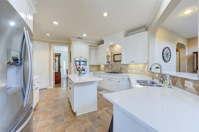 kitchen with appliances with stainless steel finishes, a sink, arched walkways, tasteful backsplash, and white cabinets
