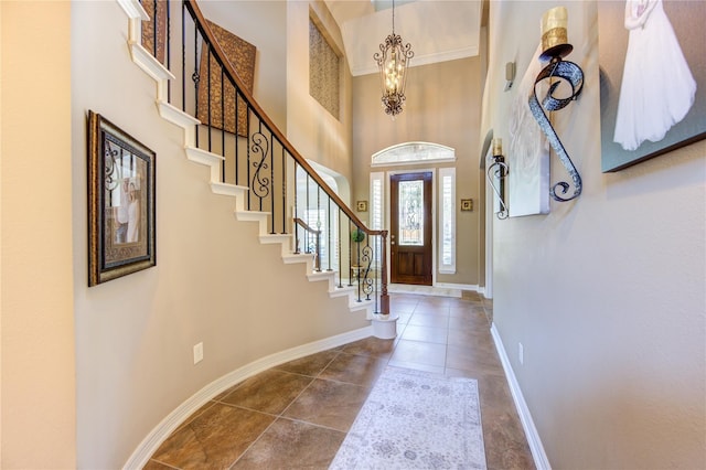 foyer with a chandelier, stairs, baseboards, tile patterned floors, and a towering ceiling