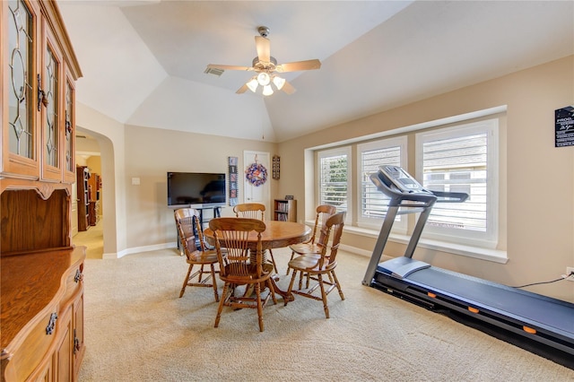 dining space featuring light carpet, baseboards, ceiling fan, lofted ceiling, and arched walkways