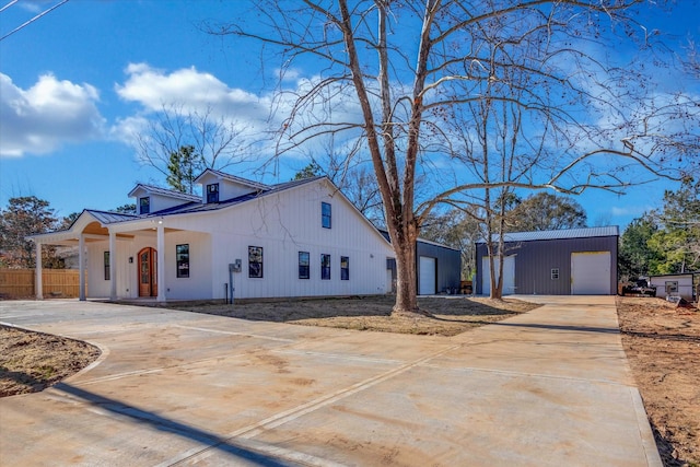view of front of house featuring an outdoor structure, concrete driveway, covered porch, metal roof, and a detached garage