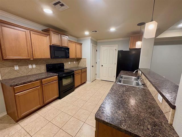 kitchen with visible vents, black appliances, dark countertops, and a sink