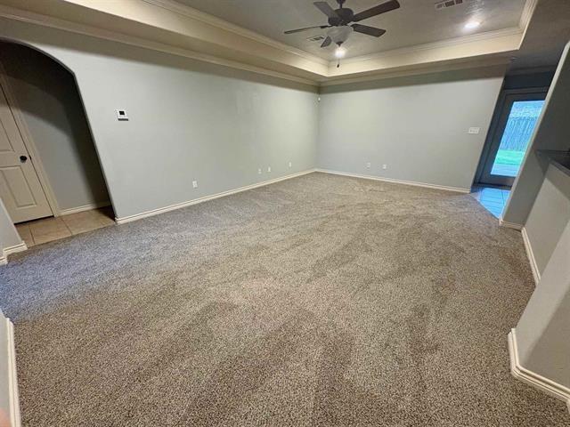 carpeted empty room featuring baseboards, ceiling fan, crown molding, and a raised ceiling