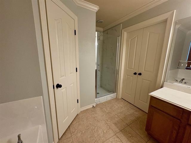 full bath featuring a stall shower, crown molding, a washtub, and vanity