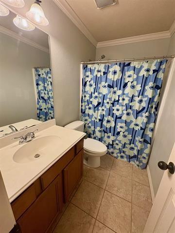 bathroom with a shower with curtain, vanity, crown molding, toilet, and tile patterned floors