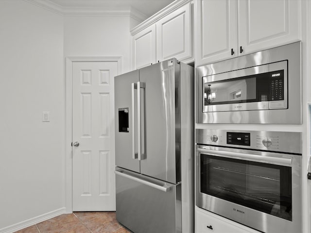 kitchen with white cabinets, ornamental molding, appliances with stainless steel finishes, and light tile patterned floors