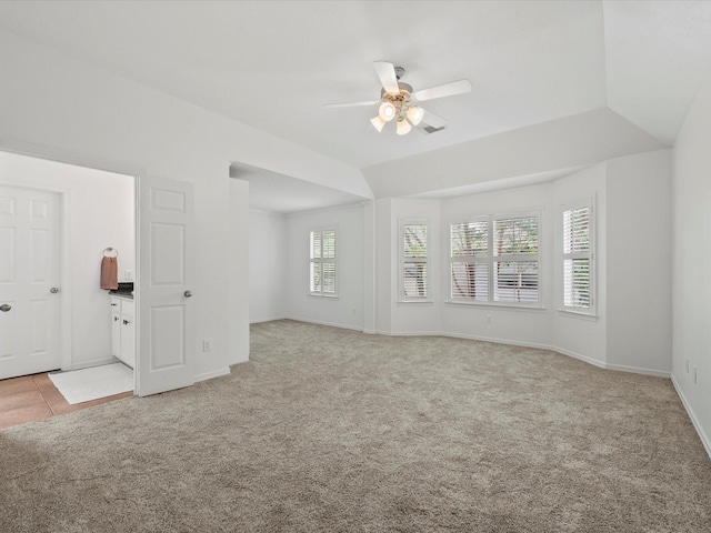 empty room featuring a ceiling fan, baseboards, lofted ceiling, and light colored carpet