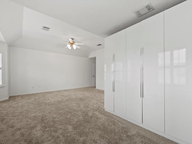 spare room with light carpet, visible vents, lofted ceiling, and a ceiling fan