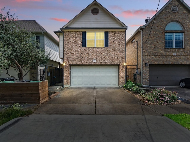 traditional-style house featuring fence, a garage, brick siding, and concrete driveway