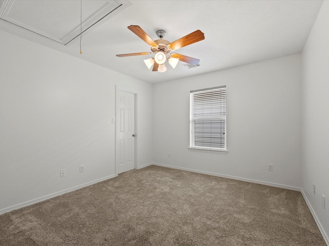 empty room featuring carpet flooring, a ceiling fan, attic access, baseboards, and visible vents