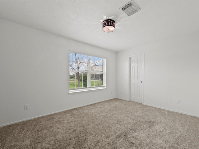carpeted spare room featuring baseboards and visible vents