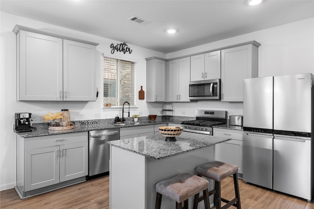 1100 Greenshank Dr, Katy, TX 77493 - kitchen with a sink, a kitchen bar, appliances with stainless steel finishes, dark stone countertops, and visible vents