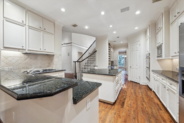5079 Cedar Creek Dr, Houston, TX 77056 - kitchen featuring stainless steel appliances, a center island, wood finished floors, recessed lighting, and backsplash