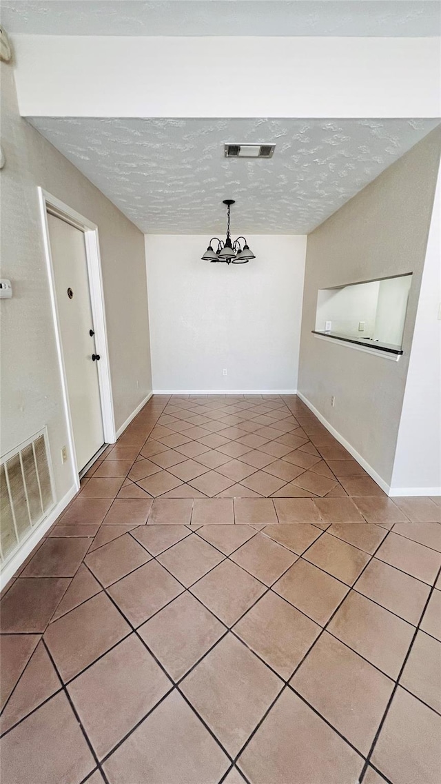 unfurnished dining area featuring light tile patterned flooring, a textured ceiling, and visible vents