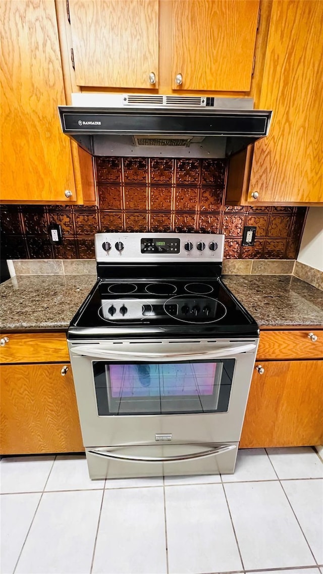 kitchen featuring light tile patterned flooring, tasteful backsplash, stainless steel electric range oven, and under cabinet range hood