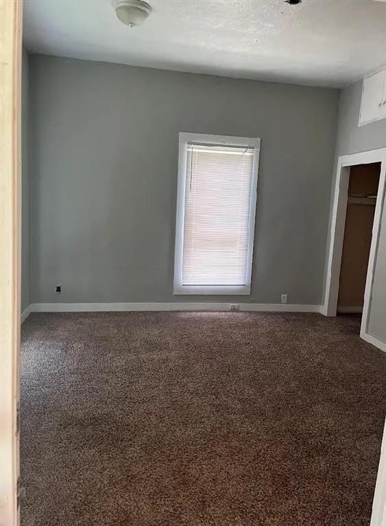 405 E Main St, Bishop, TX 78343 - spare room featuring baseboards, carpet, and a textured ceiling