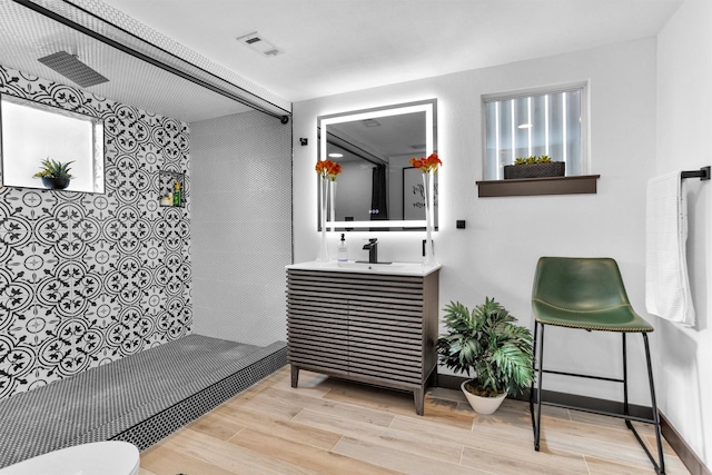 618 Lester St, Houston, TX 77007 - bathroom with tiled shower, wood finished floors, vanity, baseboards, and toilet