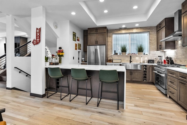 618 Lester St, Houston, TX 77007 - kitchen with premium appliances, a sink, wall chimney exhaust hood, a tray ceiling, and a kitchen breakfast bar