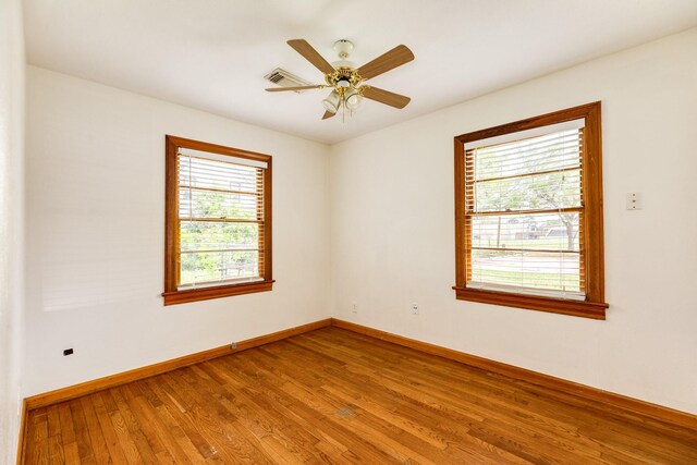 unfurnished room featuring baseboards, visible vents, wood finished floors, and ceiling fan