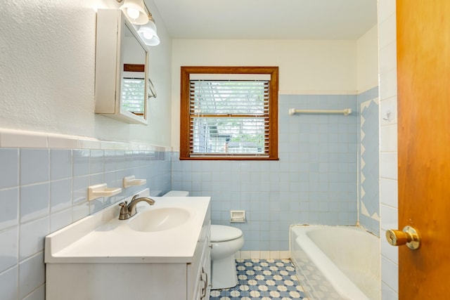 full bathroom with a bathing tub, toilet, vanity, and tile walls