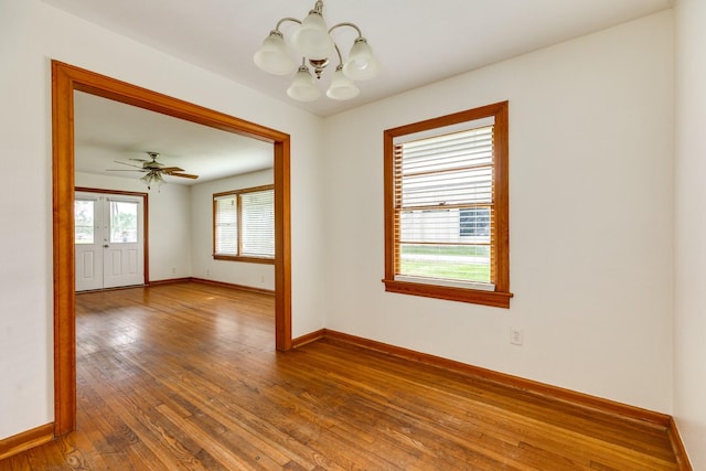 empty room featuring baseboards, a notable chandelier, and hardwood / wood-style flooring