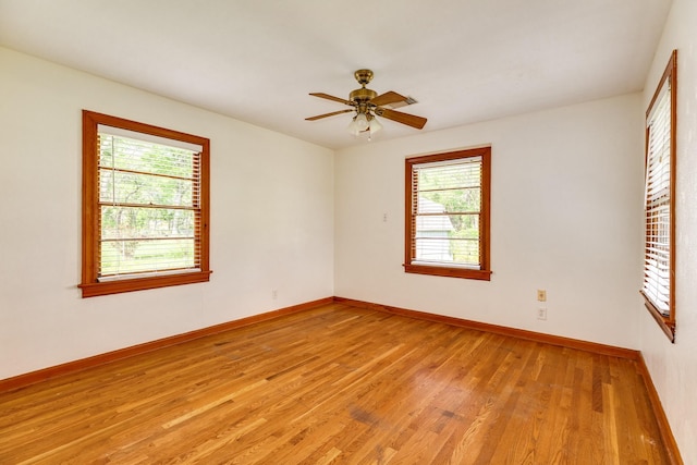 spare room featuring a ceiling fan, baseboards, and light wood-type flooring
