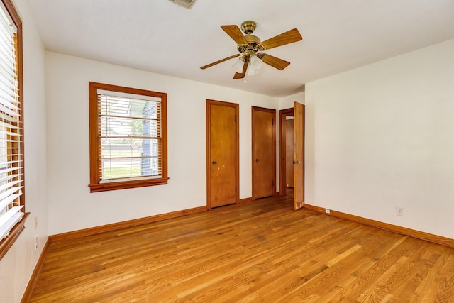 unfurnished bedroom featuring multiple closets, baseboards, and light wood finished floors