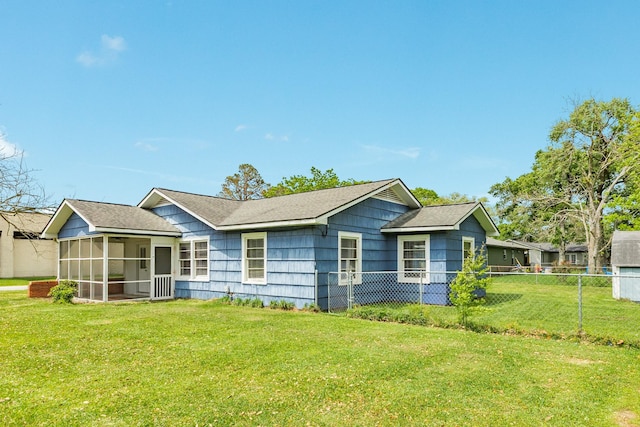 view of front facade featuring a front yard, a sunroom, a shingled roof, and fence