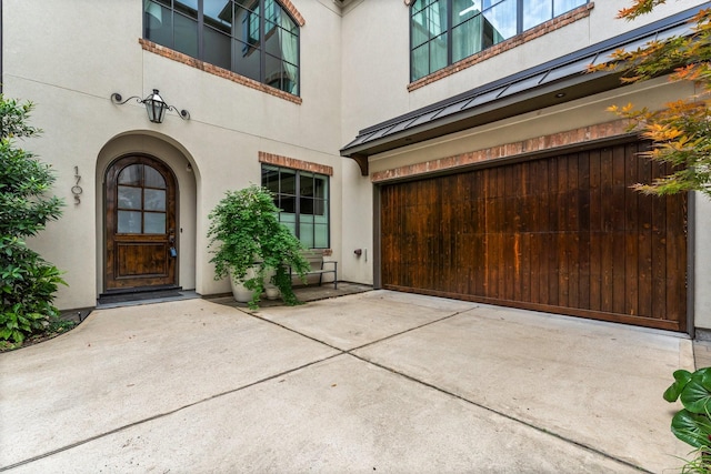 1705 Michigan St, Houston, TX 77006 - view of exterior entry with a garage, stucco siding, a standing seam roof, and driveway
