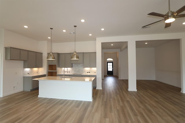 8526 Pier Cove Dr, Cypress, TX 77433 - kitchen with gray cabinets, wood finished floors, an island with sink, tasteful backsplash, and recessed lighting