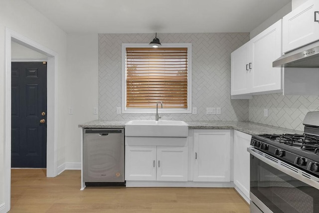 2831 Jones St, Houston, TX 77026 - kitchen featuring stainless steel appliances, light wood finished floors, under cabinet range hood, light stone counters, and white cabinetry
