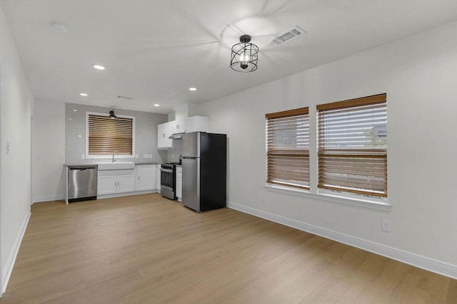 2831 Jones St, Houston, TX 77026 - kitchen featuring appliances with stainless steel finishes, white cabinets, light wood-type flooring, recessed lighting, and decorative backsplash