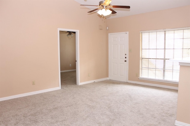 empty room featuring light carpet, a ceiling fan, and baseboards
