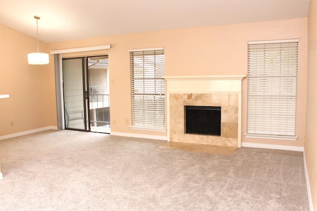 unfurnished living room featuring carpet floors, a tile fireplace, and baseboards