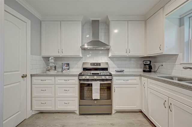 5806 Cartagena St, Houston, TX 77035 - kitchen with wall chimney exhaust hood, white cabinetry, stainless steel gas range oven, a sink, and backsplash