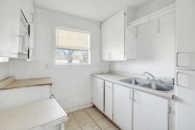2320 Westward Ave, La Marque, TX 77568 - kitchen with white cabinets, light tile patterned floors, light countertops, and a sink