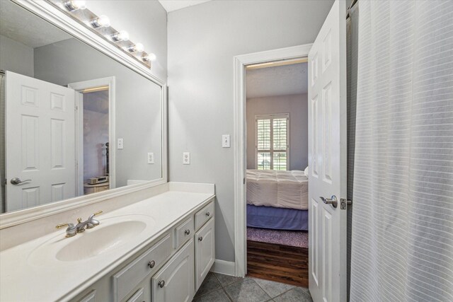 full bathroom featuring baseboards, ensuite bathroom, vanity, and tile patterned flooring