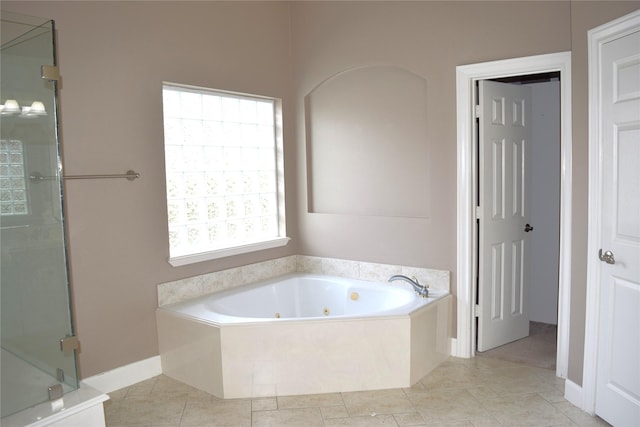 bathroom featuring baseboards, a jetted tub, a stall shower, and plenty of natural light