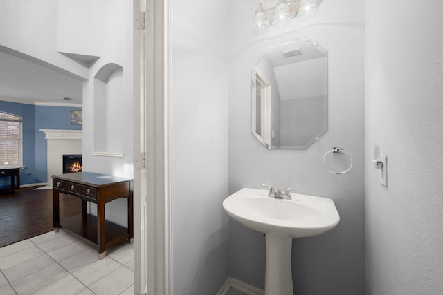 8922 Eaglecove Dr, Houston, TX 77064 - bathroom featuring tile patterned floors, crown molding, and a warm lit fireplace