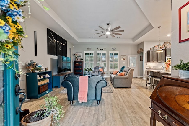 9791 Waller St, Conroe, TX 77303 - living area featuring a tray ceiling, baseboards, light wood finished floors, and a ceiling fan