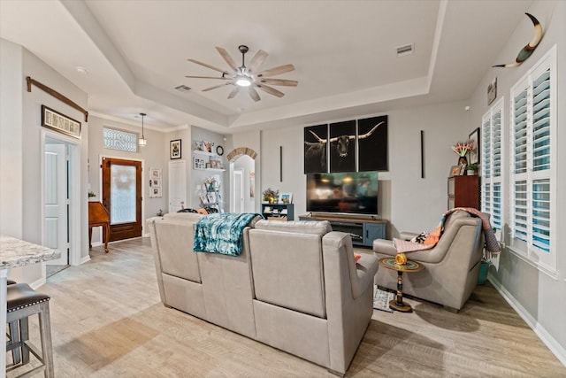 9791 Waller St, Conroe, TX 77303 - living room featuring a tray ceiling, a healthy amount of sunlight, a ceiling fan, and light wood-style flooring