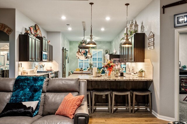 9791 Waller St, Conroe, TX 77303 - kitchen with light wood-style floors, a peninsula, stainless steel microwave, open floor plan, and backsplash