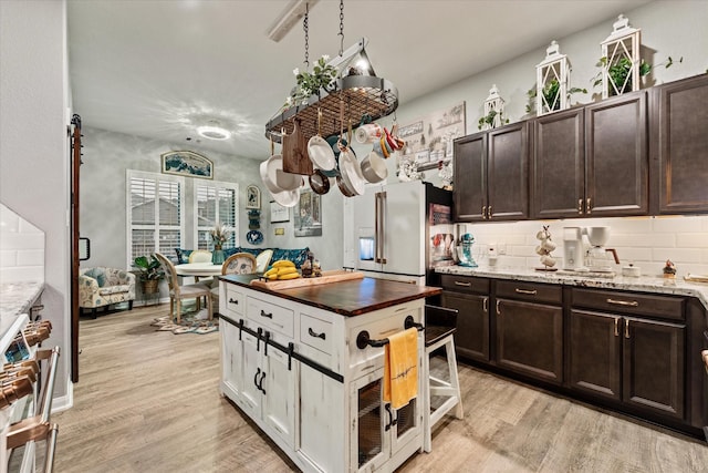9791 Waller St, Conroe, TX 77303 - kitchen featuring light wood-style floors, dark brown cabinets, white cabinetry, light stone counters, and stainless steel appliances