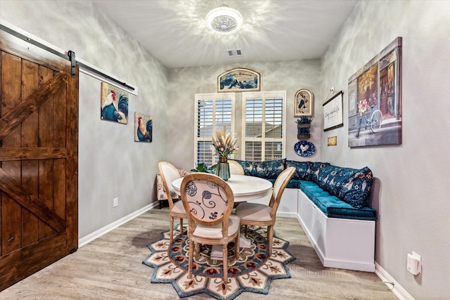 9791 Waller St, Conroe, TX 77303 - dining space featuring a barn door, visible vents, baseboards, and wood finished floors