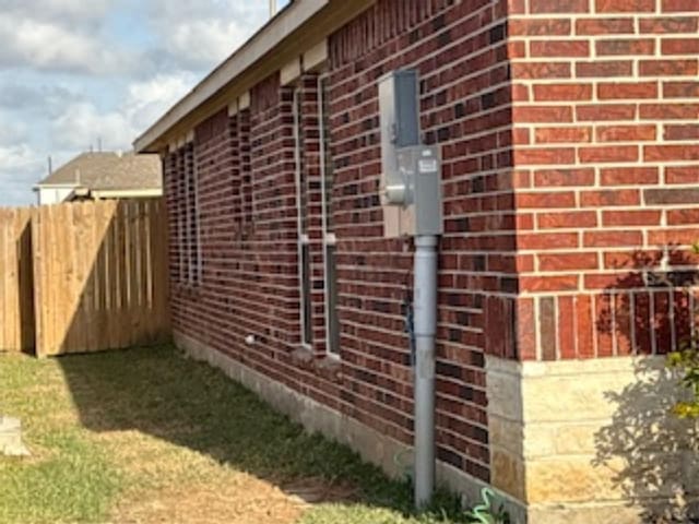 view of side of property with brick siding and fence