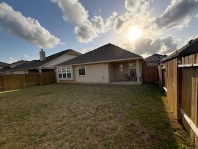 rear view of house with a fenced backyard, a patio area, and a yard