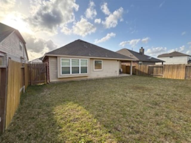 back of house with a fenced backyard and a lawn
