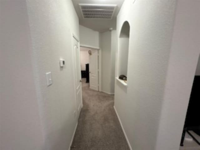 hallway featuring arched walkways, carpet, baseboards, and visible vents